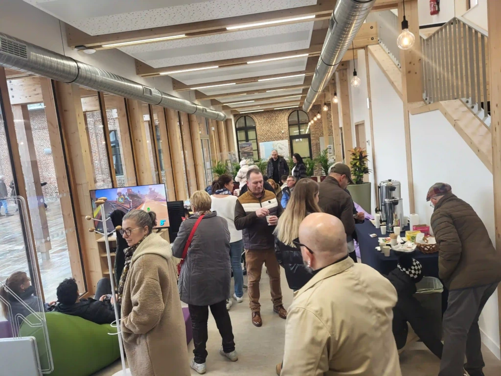 la médiathèque du Crotoy. Un groupe de personnes est rassemblé debout au centre, dont certaines boivent du café à une table à droite.